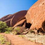 Uluru towering over the Australian outback, showcasing its immense size and reddish hue