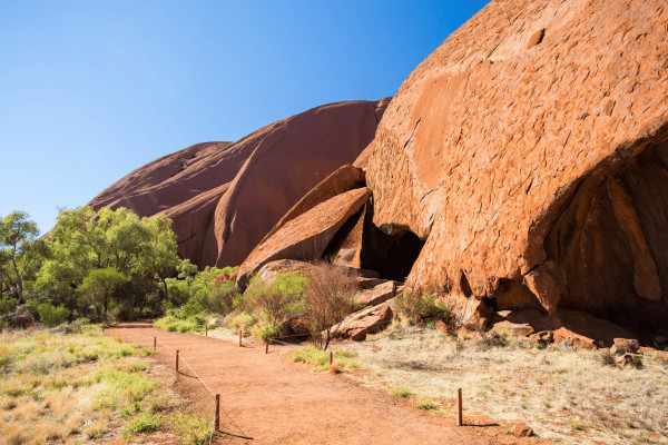 Uluru towering over the Australian outback, showcasing its immense size and reddish hue