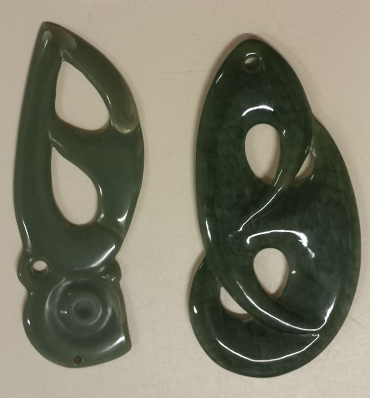 A close up of a jade ornament, green and shiny. The artifact showcases intricate carvings and a polished surface, highlighting its cultural value and artistic craftsmanship.