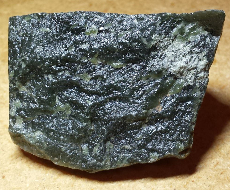 A dark coloured rock with light coloured glassy parts.