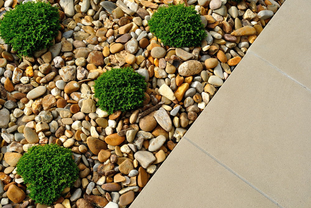 Landscaping rock with weeds growing through, showing the aesthetic problem of weeds in rock gardens