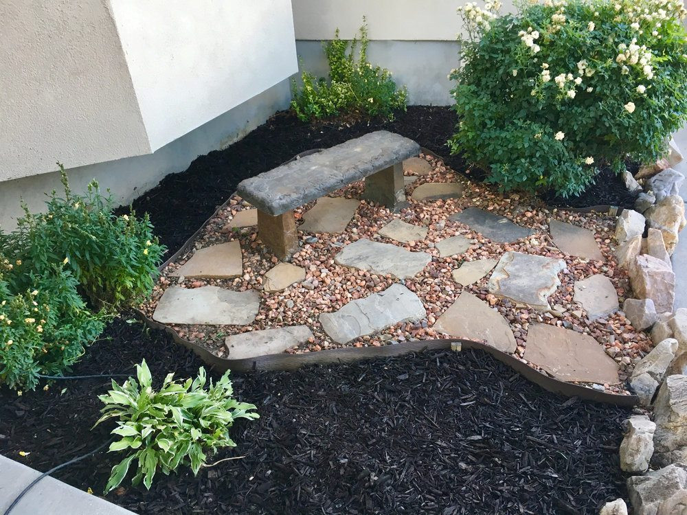 A Newly Landscaped Flowerbed With Flat Rocks, Stones and Stone Seating 