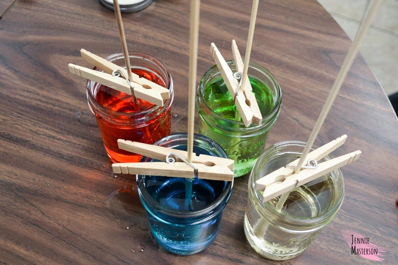 four mason jars filled with rock candy solution and have skewers placed in them