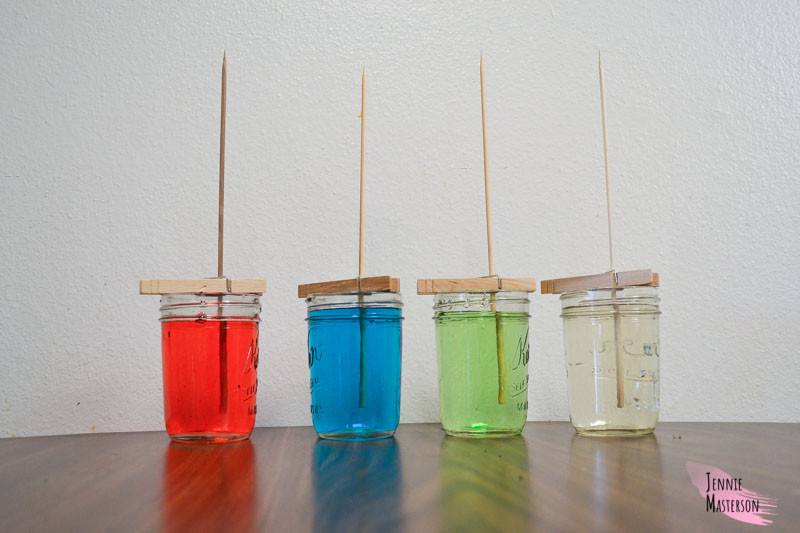 four mason jars filled with the sugar crystal solution
