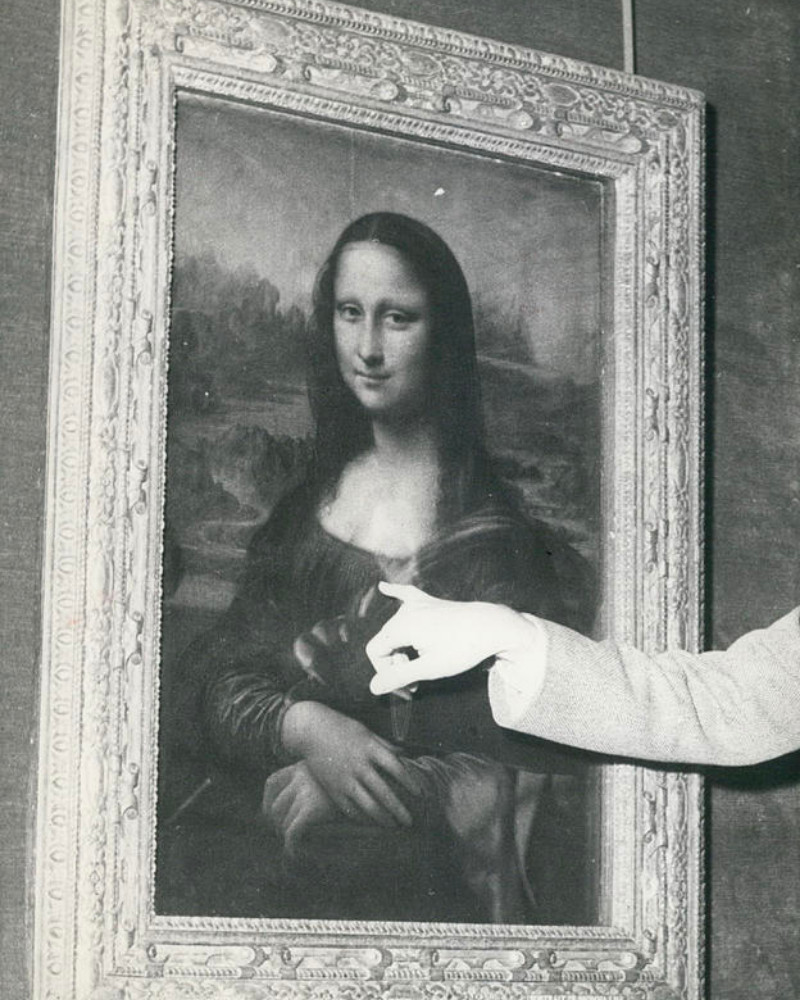Black and white photo of the Mona Lisa with a hand pointing out damage to the portrait