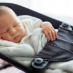 Newborn sleeping in inclined swing