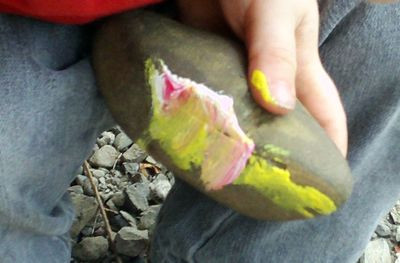 Close-up of a hand painting a rock with colorful paint
