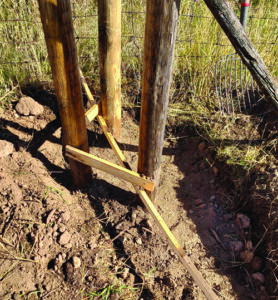 Partially filled rock fence post hole showcasing the mixture of dirt and rocks, setting the stage for a sturdy foundation