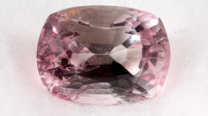 Poudretteite gemstone, illustrating its naturally pink color and discovery at Mont Saint-Hilaire in Quebec.