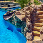 Pool rock slide with natural stone steps leading to the top