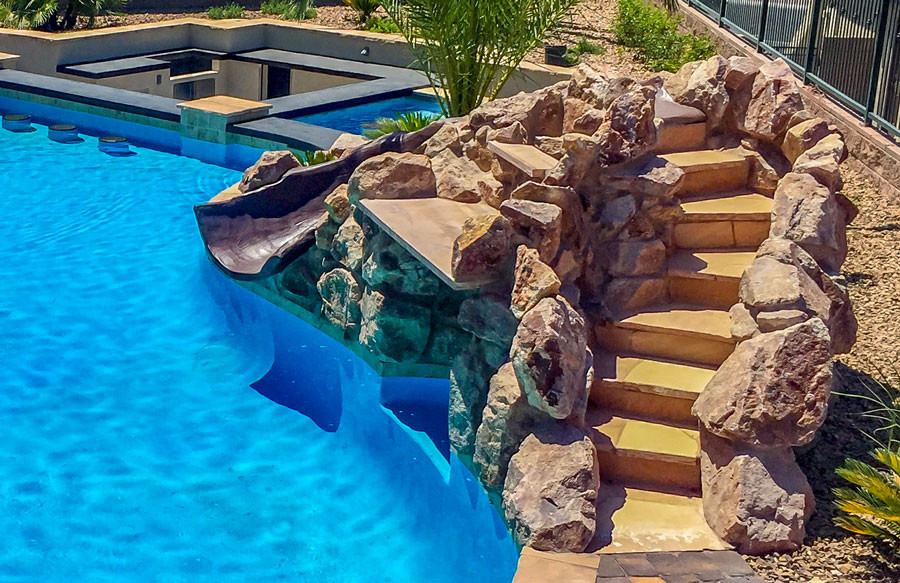 Pool rock slide with natural stone steps leading to the top