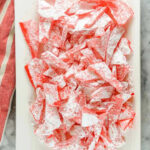 A close up of bright red rock candy crystals dusted with powdered sugar.