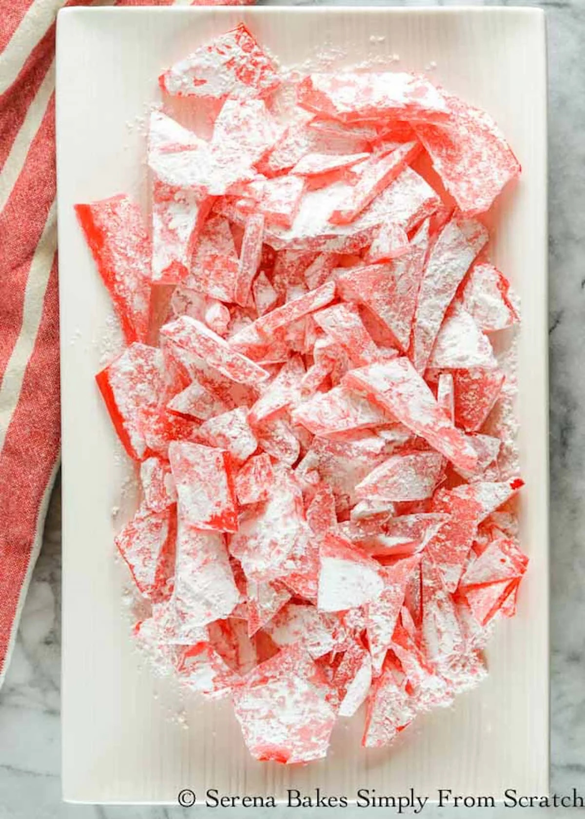 A close up of bright red rock candy crystals dusted with powdered sugar.