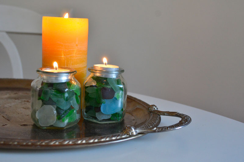 A pedestal candle holder filled with seashells and a tea light, positioned next to old books, creating a vintage-inspired decorative accent.