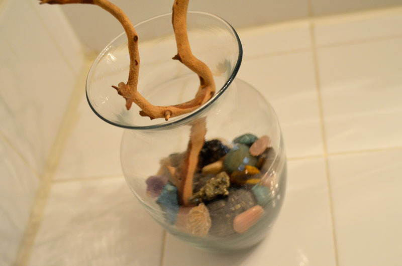 Rocks and crystals arranged in a simple, clear glass vase, offering a decorative touch and a connection to nature within a bathroom setting.