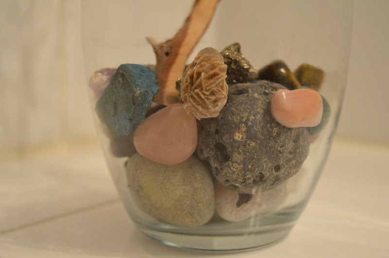 Rock collection display in a glass vase with a manzanita branch, showcasing a simple yet elegant decorative element for a bathroom counter.