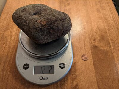Cobblestone on a scale indicating its weight as 1212 grams
