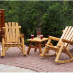 Wooden rocking chair on a porch with a view of a lake.