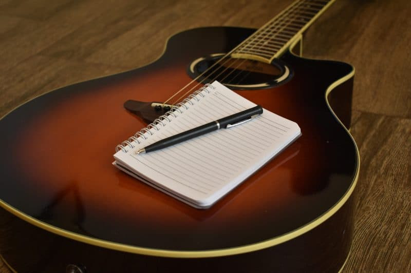 Acoustic guitar with a notebook, symbolizing the creative process of songwriting and musical expression