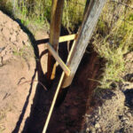 Sticks holding posts in place with small sticks nailed between wooden posts for correct distance, ensuring a stable foundation
