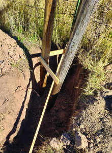 Sticks holding posts in place with small sticks nailed between wooden posts for correct distance, ensuring a stable foundation