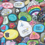 Assortment of colorful painted rocks displayed on a mossy surface, perfect for outdoor decoration