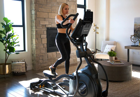 Woman using Sole E35 elliptical machine at home, highlighting stable design and minimizing wobble during workout.